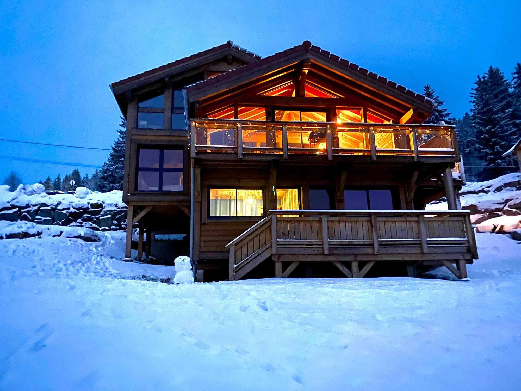 Le chalet illuminé sous la neige à la tombée de la nuit