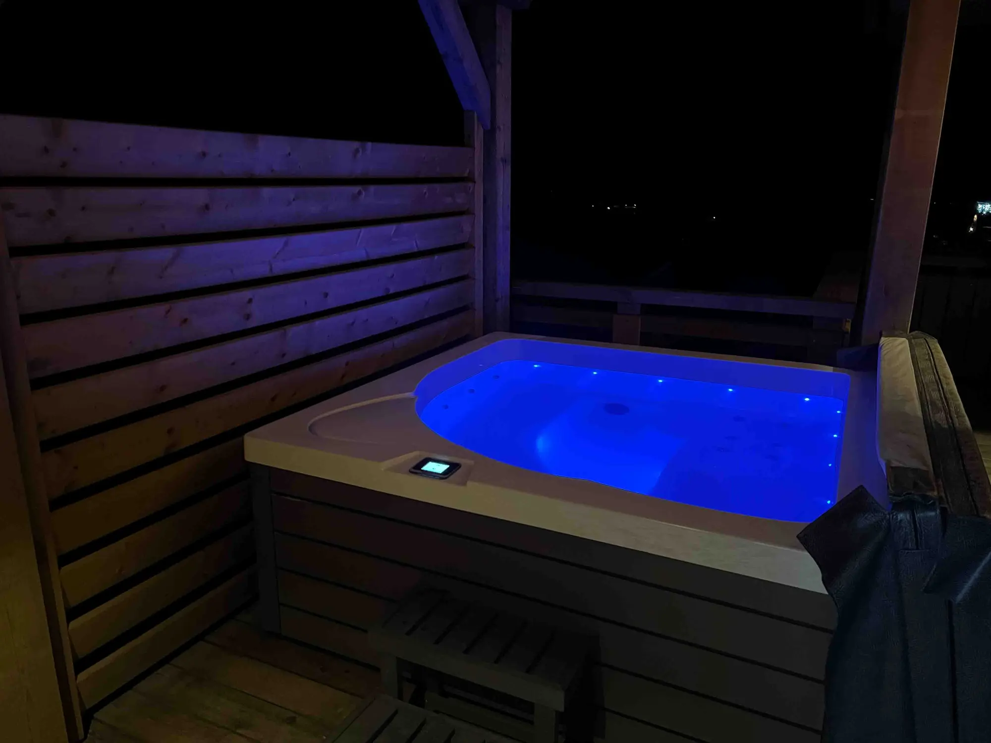 Jacuzzi extérieur du chalet éclairé la nuit sur la terrasse
