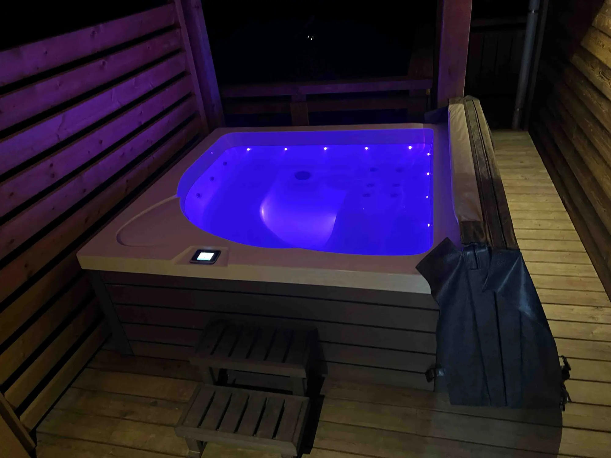 The chalet's outdoor hot tub lit up at night on the terrace
