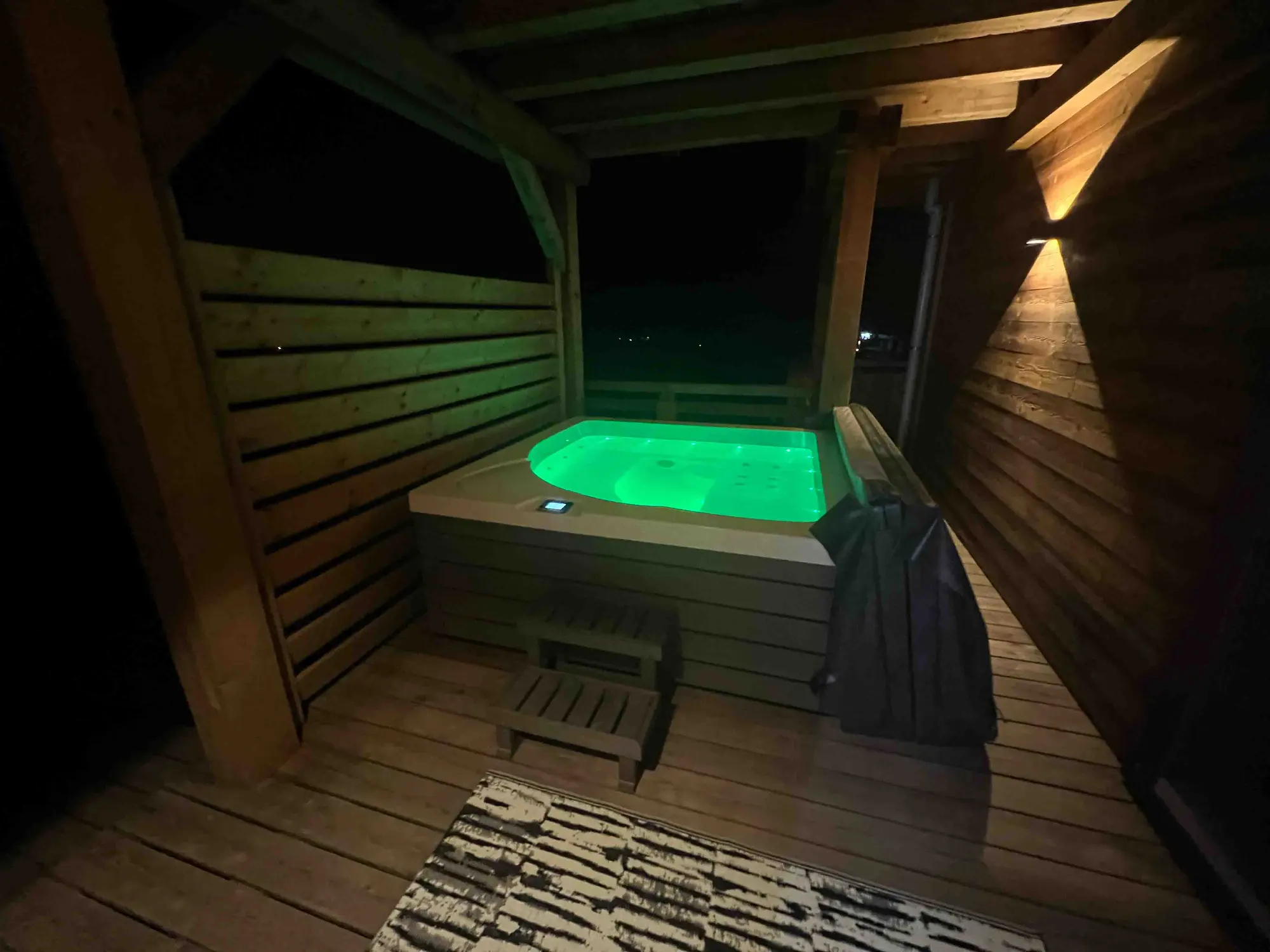 The chalet's outdoor hot tub lit up at night on the terrace