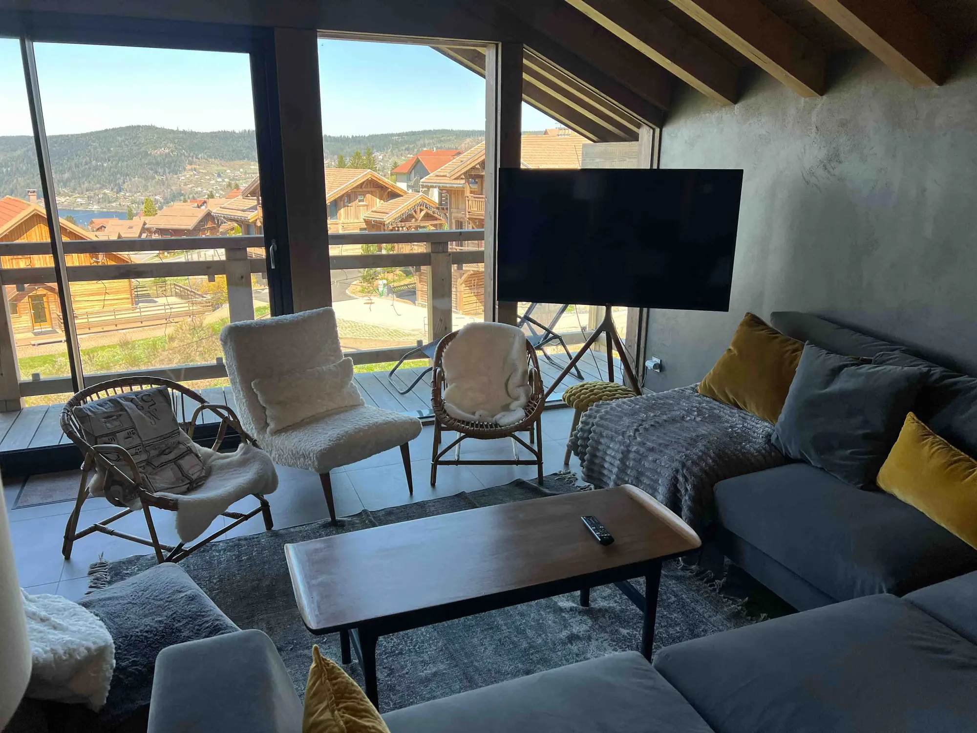 Salon du chalet ouvert sur les baies vitrées et la vue sur le lac