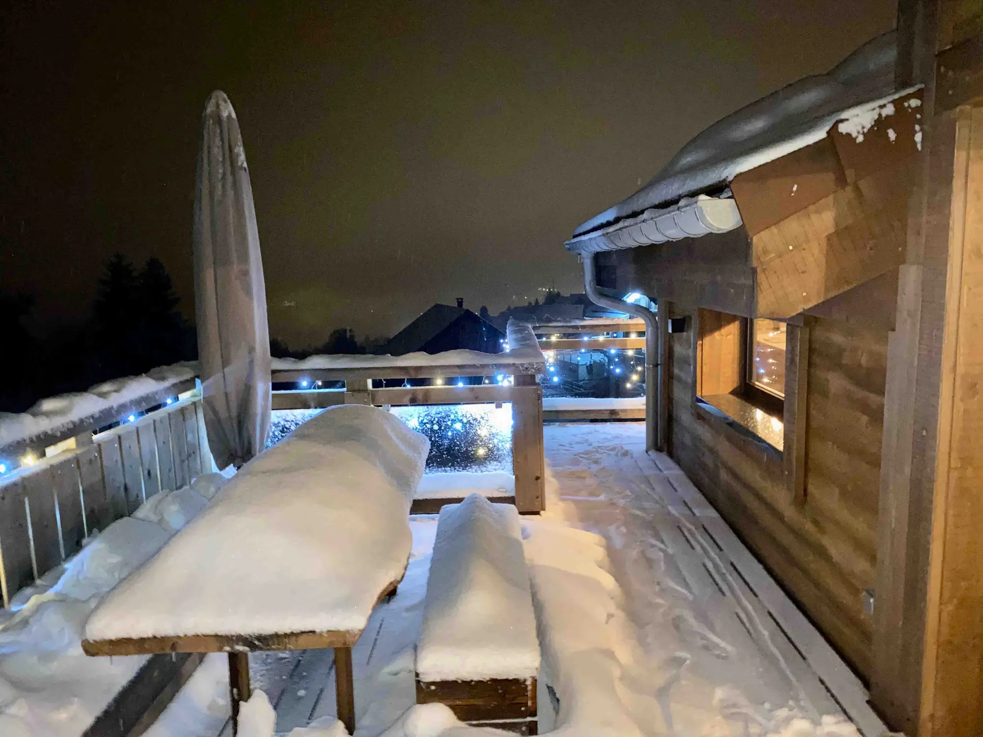 The chalet terrace lit at night, hot tub glowing