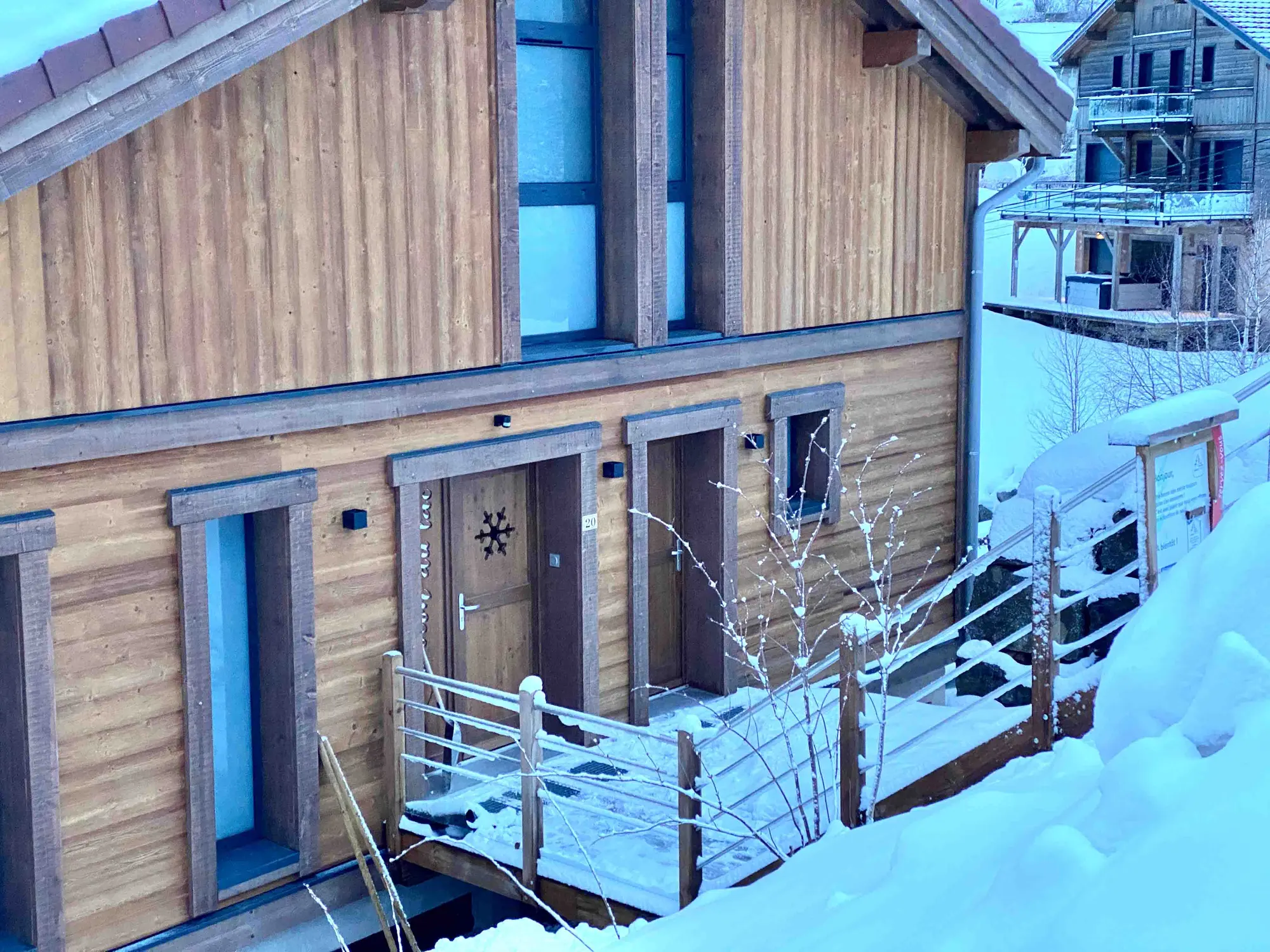 Le chalet illuminé sous la neige à la tombée de la nuit